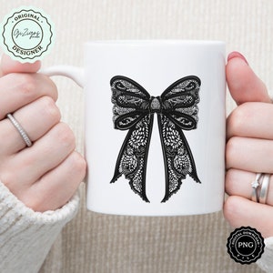 May include: White ceramic mug with a black lace bow design. The mug is held by a hand.