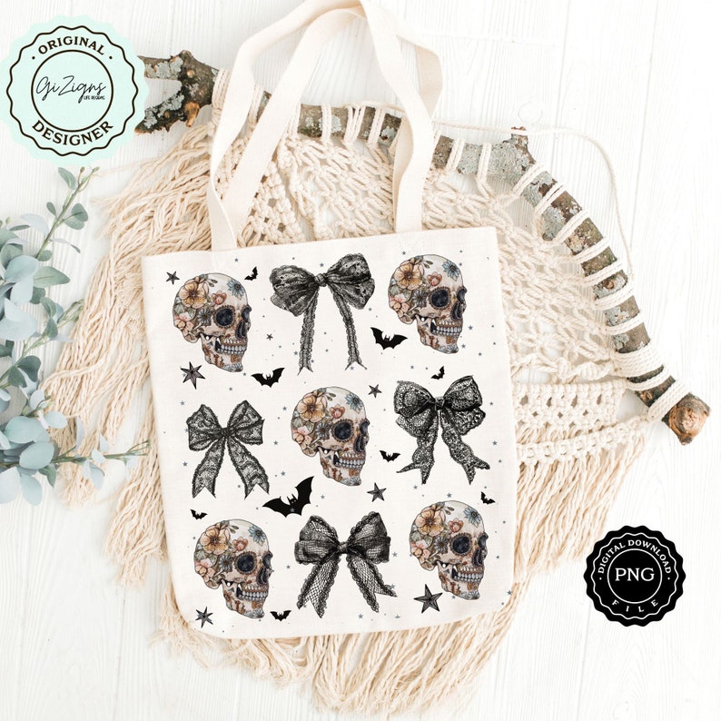 May include: A cream-colored tote bag featuring a repeating pattern of floral-decorated skulls, black bows, bats, and stars. The bag has long, natural-colored handles. The words "ORIGINAL DESIGNER" are in a circular logo on the upper left.