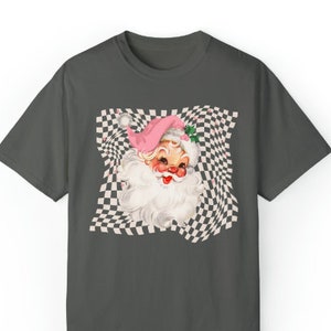 May include: A dark gray t-shirt with a vintage illustration of Santa Claus's face on a checkered background. The checkered pattern is distorted, creating a swirling effect.