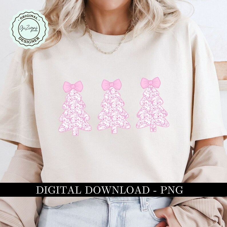 Pu&ograve; includere: Una maglietta bianca con tre alberi di Natale rosa con fiocchi in cima. Gli alberi sono fatti di un motivo di piccoli cuori rosa. Il testo "DOWNLOAD DIGITALE - PNG" &egrave; in fondo alla maglietta.
