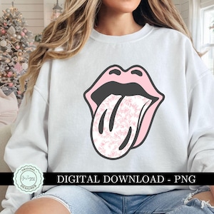 K&ouml;nnte beinhalten: Ein wei&szlig;er Pullover mit einer pinkfarbenen und schwarzen Grafik einer Zunge, die aus einem Mund herausragt. Die Zunge hat ein Blumenmuster.