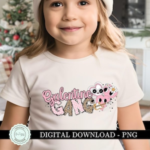 May include: A white t-shirt with a pink and black graphic design that says "Galentine Gang". The graphic features a heart with a face and a guitar.