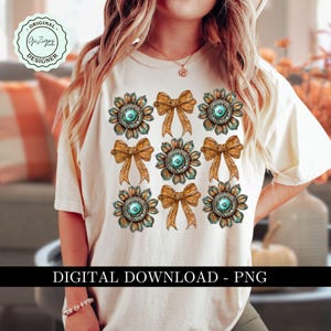 May include: A white t-shirt with a design of nine turquoise and gold bows and flowers. The design is repeated nine times on the shirt. The shirt has the text "Original Designer" on it.