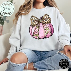 Pode incluir: Uma ab&oacute;bora rosa com um design floral e um la&ccedil;o de estampa de leopardo. A ab&oacute;bora est&aacute; sobre um fundo branco.
