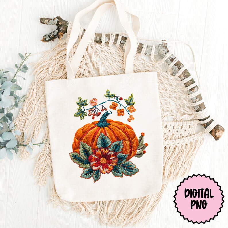 Peut inclure: Un sac fourre-tout blanc avec une citrouille brod&eacute;e color&eacute;e et un motif floral. La citrouille est orange avec des feuilles vertes et une fleur rouge. Le motif rappelle un motif de broderie vintage.