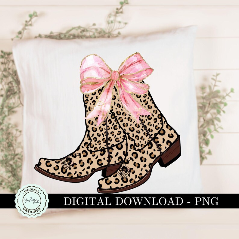 K&ouml;nnte beinhalten: Ein Paar braune und schwarze Cowboy-Stiefel mit Leopardenmuster und einer rosa Schleife oben. Die Stiefel haben eine spitze Zehenpartie und einen hohen Absatz. Der Hintergrund ist wei&szlig;.