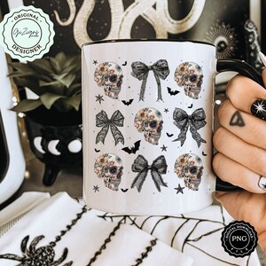 May include: White ceramic mug with a black interior and handle, featuring a repeating pattern of floral skull illustrations, black bows, bats, and stars. The mug has the text "Original Designer" and "PNG File" on it.