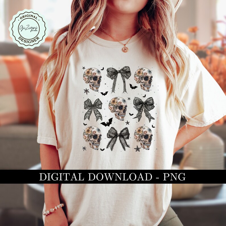 May include: Cream-colored t-shirt featuring a repeating pattern of floral skulls and black bows, with bats and stars. The words "DIGITAL DOWNLOAD - PNG" are printed at the bottom. The shirt has a relaxed fit.