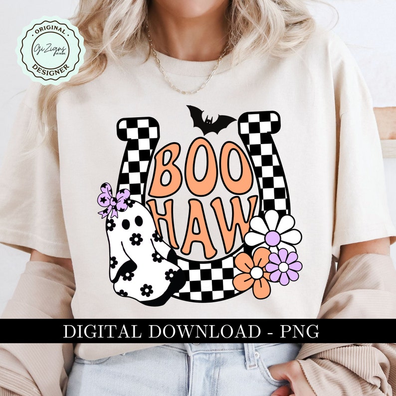 May include: Cream-colored t-shirt with a Halloween-themed graphic. The design features the words "BOO HAW" in orange, a ghost, flowers, and a bat. The design is set against a horseshoe shape with a checkered pattern. The text "DIGITAL DOWNLOAD - PNG" is at the bottom.