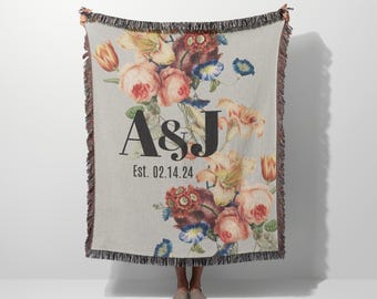 May include: A woven throw blanket with a floral pattern and the text "A&J Est. 02.14.24" in black.