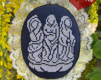 May include: A navy blue embroidered piece with a white cross-stitch design of three figures, framed by cream lace and yellow flowers. The text "CROSS STITCH PATTERN PDF" is in a red heart shape.
