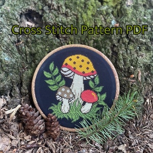 May include: Cross stitch pattern PDF featuring a mushroom design. The mushrooms are red, yellow, and white with black spots. The background is black with green leaves.