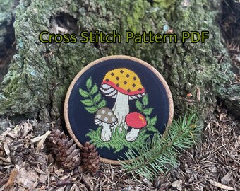 May include: Cross stitch pattern PDF featuring a mushroom design. The mushrooms are red, yellow, and white with black spots. The background is black with green leaves.