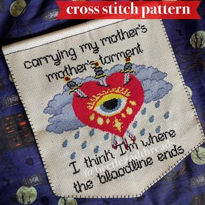 Puede incluir: Patrón de punto de cruz con el texto "carrying my mother's mother's torment" y "I think I'm where the bloodline ends." El diseño presenta un corazón rojo atravesado por tres espadas, un ojo y una nube azul.