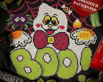 May include: Cross stitch pattern PDF for a Halloween ghost with a bow tie and the word "BOO" in green letters. The ghost is holding a spider and a candy corn.