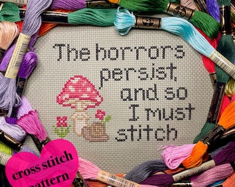 May include: Cross stitch pattern featuring a mushroom and the text "The horrors persist, and so I must stitch". The pattern is surrounded by colourful embroidery floss.