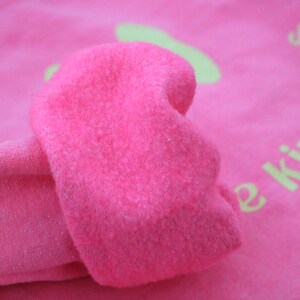 Pode incluir: Camisola cor-de-rosa com um design bordado amarelo que diz "Spread Kindness".