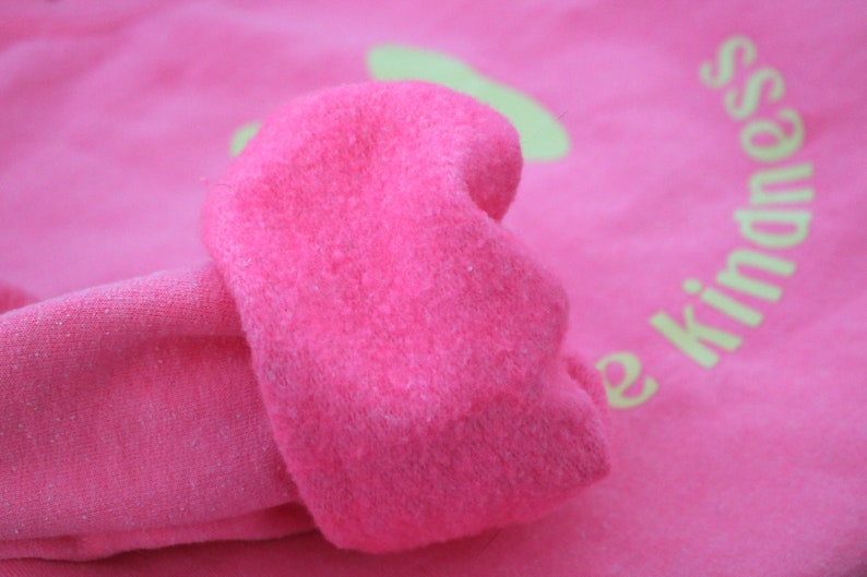 Pode incluir: Camisola cor-de-rosa com um design bordado amarelo que diz "Spread Kindness".