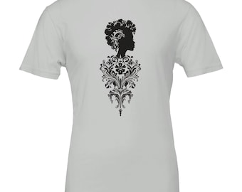 Puede incluir: Una camiseta gris claro con una silueta negra del perfil de una mujer, un afro y un diseño floral decorativo. El diseño está centrado en la camiseta y se extiende por el torso.