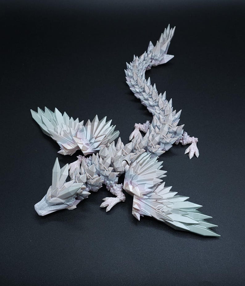 Puede incluir: Una figura de drag&oacute;n articulada de color blanco con una textura geom&eacute;trica compleja similar a un cristal que cubre todo el cuerpo, incluidas las alas y la larga cola segmentada. La superficie tiene sutiles reflejos iridiscentes y bordes afilados.