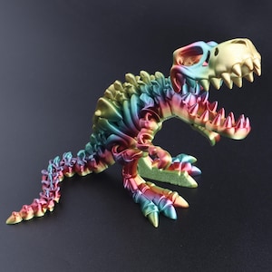 May include: A multi-colored, articulated dinosaur skeleton figurine featuring a gradient of rainbow hues including blue, green, yellow, and red. The T-Rex figure is depicted in a dynamic, open-mouthed pose with visible segmented joints along its spine.