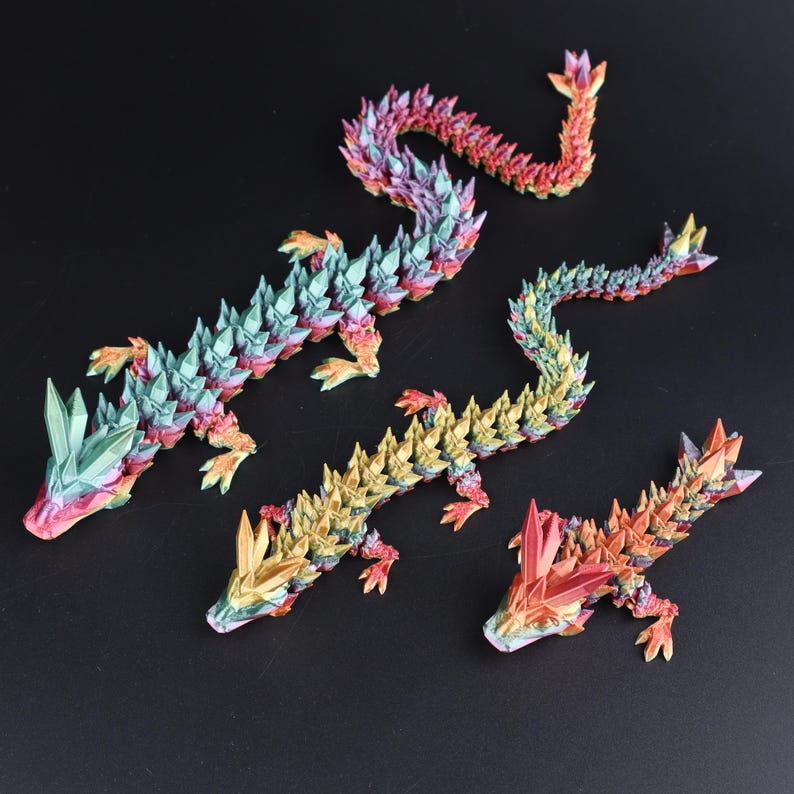 May include: Four colorful, geometric dragon figurines in shades of red, orange, yellow, green, and purple. The dragons have a crystalline appearance and are arranged on a black surface.