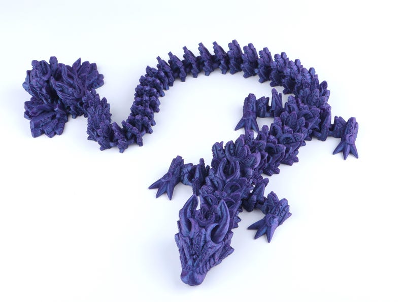 May include: A dark purple articulated dragon figurine with a segmented body, detailed scales, and sharp claws. The creature features a long, winding tail and a head with prominent horns, showcasing a complex, layered design throughout its entire form.