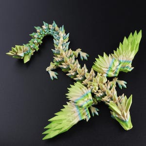 Puede incluir: Una figura de drag&oacute;n articulada con m&uacute;ltiples uniones que presenta una textura geom&eacute;trica similar al cristal. La criatura est&aacute; coloreada en un degradado de verde lima, amarillo p&aacute;lido y azul suave, con escamas angulares en todo el cuerpo.