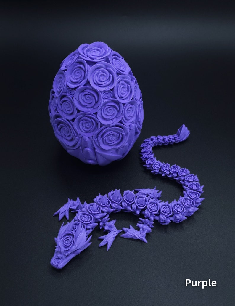 May include: A purple 3D printed articulated dragon figure with a rose-patterned texture, accompanied by a matching purple egg covered in sculpted roses. The dragon features a long, segmented body and a detailed head, both adorned with rose motifs.