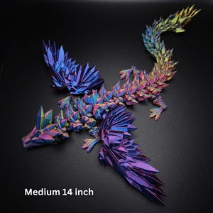 Puede incluir: Una figura de drag&oacute;n articulada de 35,56 cm con una estructura geom&eacute;trica similar a un cristal y un acabado iridiscente vibrante que cambia entre tonos azul profundo, p&uacute;rpura, magenta y dorado en sus alas, cuerpo y larga cola.