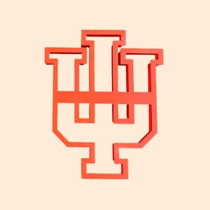 以下が含まれることがあります： インディアナ大学のロゴの形をした赤いクッキーカッター。ロゴはスタイリッシュな「IU」で、「I」が「U」と重なっています。
