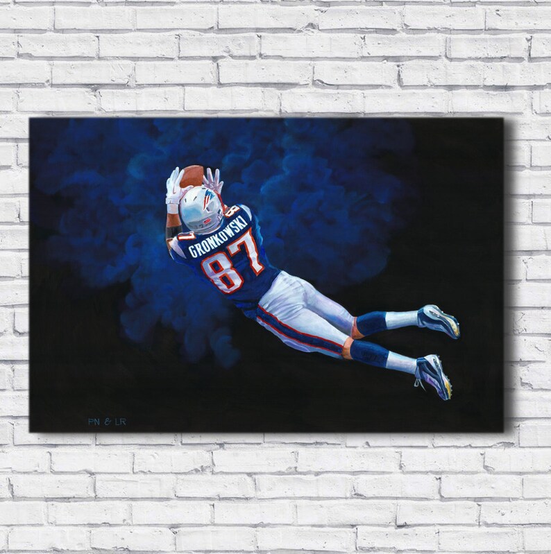 May include: A painting of a football player in a blue and white uniform, catching a football. The player is mid-air, reaching for the ball with outstretched arms. The jersey number 87 is visible. The background is dark with blue accents.