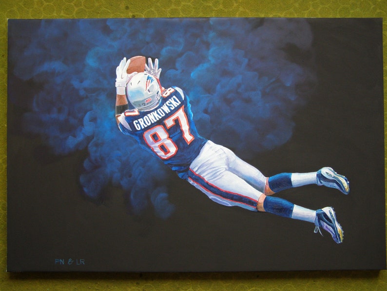 May include: An oil painting of a football player in a blue and white uniform, catching a brown football. The player is mid-air against a dark background with blue smoke effects. The jersey reads "GRONKOWSKI 87".