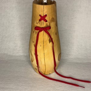 May include: A wooden vase with a clear glass insert, decorated with red laces tied in a bow. The vase has a natural wood finish and a unique, organic shape.