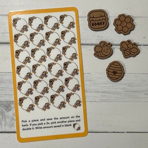 May include: A sheet of stickers with a bee theme. The stickers feature bees, honeycombs, and jars of honey. The sheet is yellow with a white border. The text on the sheet reads: "Pick a piece and save the amount on the back. If you pick a 2x, pick another piece and double it. Write amount saved in blank"