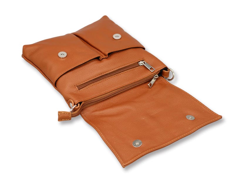 Peut inclure: Un sac bandouli&egrave;re en cuir marron clair avec un rabat et deux fermetures &agrave; bouton-pression. Le sac poss&egrave;de une poche zipp&eacute;e et une petite sangle. Le sac est ouvert, r&eacute;v&eacute;lant l'int&eacute;rieur.