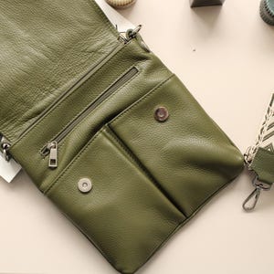 Peut inclure: Sac bandouli&egrave;re en cuir vert olive avec compartiment principal zipp&eacute; et poches avant. Le sac a une fermeture &eacute;clair et des accessoires argent&eacute;s. Une bandouli&egrave;re &agrave; motifs avec un fermoir argent&eacute; est attach&eacute;e.