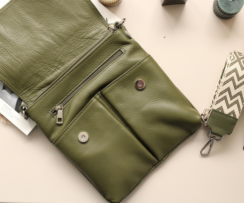 Peut inclure: Sac bandouli&egrave;re en cuir vert olive avec compartiment principal zipp&eacute; et poches avant. Le sac a une fermeture &eacute;clair et des accessoires argent&eacute;s. Une bandouli&egrave;re &agrave; motifs avec un fermoir argent&eacute; est attach&eacute;e.