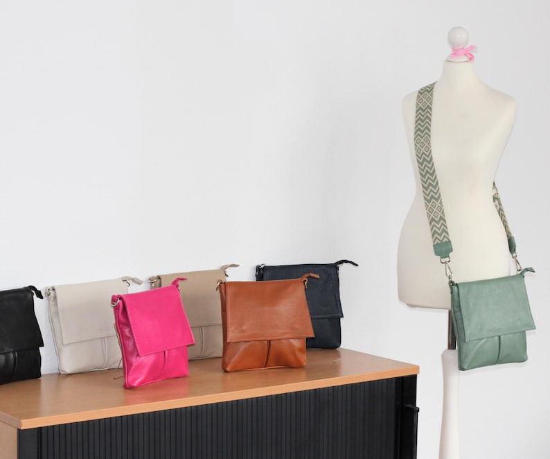 Peut inclure: Plusieurs sacs &agrave; bandouli&egrave;re en cuir de diff&eacute;rentes couleurs, dont noir, cr&egrave;me, rose vif, beige, marron et marine. Un sac est pr&eacute;sent&eacute; sur un mannequin avec une bandouli&egrave;re &agrave; motifs. Les sacs ont une fermeture &agrave; rabat et des bretelles r&eacute;glables.