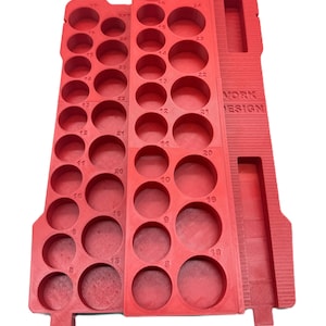 May include: A red plastic organizer with numbered compartments for storing small items. The organizer has two sections, one with a larger compartment and the other with smaller compartments. The text "WORK DESIGN" is printed on the organizer.