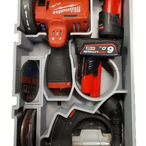 Op de afbeelding: Een grijze kunststof gereedschapsopbergkoffer met een rode en zwarte Milwaukee FUEL slijpmachine, een rode en zwarte 9,0 Ah REDLITHIUM accu en een zwarte en grijze cirkelzaag.