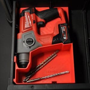 Może przedstawiać: Czerwono-szara wiertarka Milwaukee FUEL 6.0 Ah RedLithium z uchwytem na wiertła. Wiertarka znajduje się w czerwonym plastikowym organizerze z nadrukiem "WORK DESIGN".