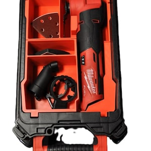 Puede incluir: Una caja de herramientas negra y roja con un inserto de espuma roja. El inserto tiene compartimentos para una herramienta oscilante Milwaukee FUEL, almohadillas de lijado y otros accesorios. La caja tiene una manija negra y una tapa transparente.