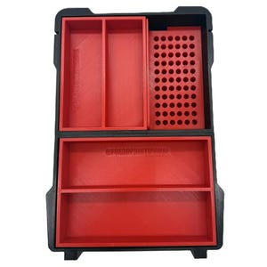 Può includere: Una scatola di contenimento in plastica nera con scomparti rossi. La scatola ha uno scomparto a griglia, uno scomparto lungo e due scomparti più piccoli. Il testo "@FOR3DPRINTINGUSA" è stampato sul fondo della scatola.