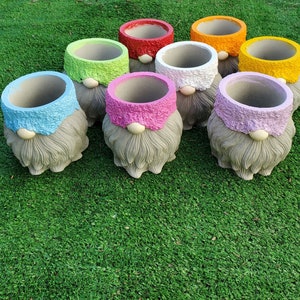 May include: Set of ten small gray gnome-shaped planters with colorful painted rims. The planters are made of concrete and have a textured surface.