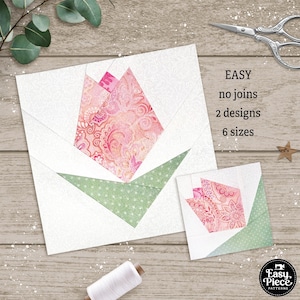 May include: Two pink and green fabric patchwork tulip flower blocks. The larger block is 12 inches and the smaller block is 6 inches. The blocks are on a wood background. The text "EASY no joins 2 designs 6 sizes" is on the right side of the image.