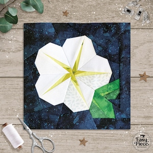 May include: A white and yellow flower quilt block on a dark blue background. The flower has white petals with yellow accents and green leaves. The block is surrounded by quilting supplies, including scissors and thread.