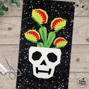 May include: A rectangular fabric quilt block featuring a white skull-shaped planter containing four green Venus flytrap plants with red interiors. The background is black with a gold star pattern. The text Easy Piece Patterns is in the corner.