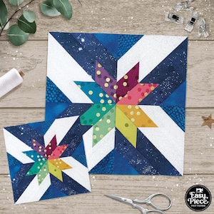 May include: Two quilt blocks featuring a colorful starburst design on a blue and white background. The larger block is 12 inches square and the smaller block is 6 inches square. The blocks are made with a variety of fabrics, including blue, white, green, yellow, orange, red, and purple. The starburst design is made with a variety of fabrics, including polka dots, stripes, and solids.