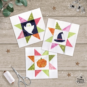 Può includere: Tre blocchi di trapunte a tema Halloween. Ogni blocco presenta un design a stella con un'immagine centrale: un fantasma, un cappello da strega e una zucca. I blocchi sono realizzati in tessuto colorato nelle tonalità di rosa, verde, arancione e blu navy.